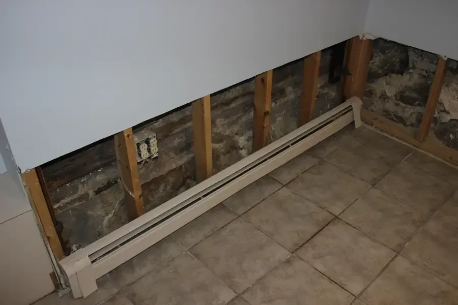 Drywall cut away above the baseboard along a wall during structural drying
