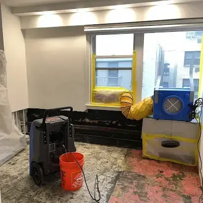 Dehumidifier and air mover drying a room after the flooring was pulled up