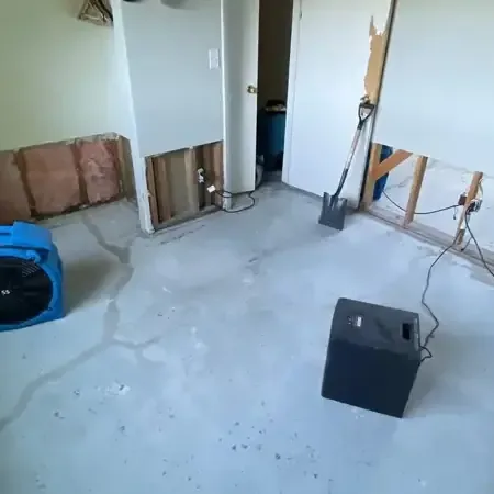 Air movers and a dehumidifier set up beside opened lower walls