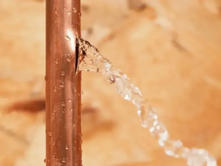 Water spraying out of a burst supply pipe inside a house