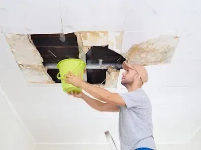 A stained ceiling cut open to reach the wet framing after a roof leak