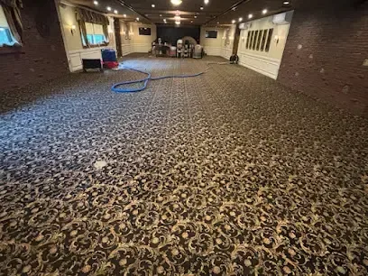 An extraction hose stretched along the wet carpet of a long commercial hallway