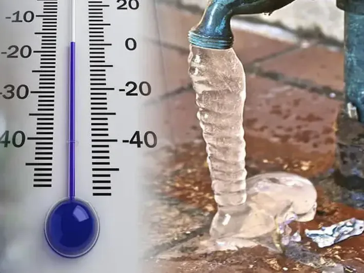 An outdoor hose bib coated in ice next to a thermometer reading below freezing