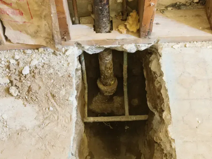 A trench cut into a concrete slab floor to expose a leaking water line
